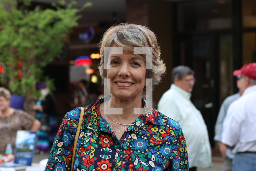 face of a woman standing outdoors with a purse on her shoulder 