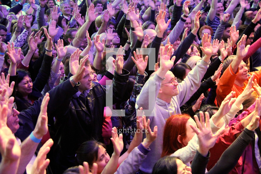 Worshippers with arms raised at a church service. People making a decision for Christ at an evangelistic outreach.