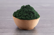 A Wooden Bowl Full of Spirulina Powder on a Wood Background