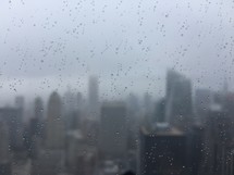 wet fogged glass window and blurry view of a city 