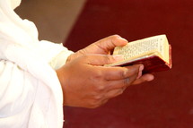 Orthodox Ethiopian woman in prayer reading the Ethiopic Bible 