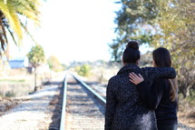 sisters standing on railroad tracks 