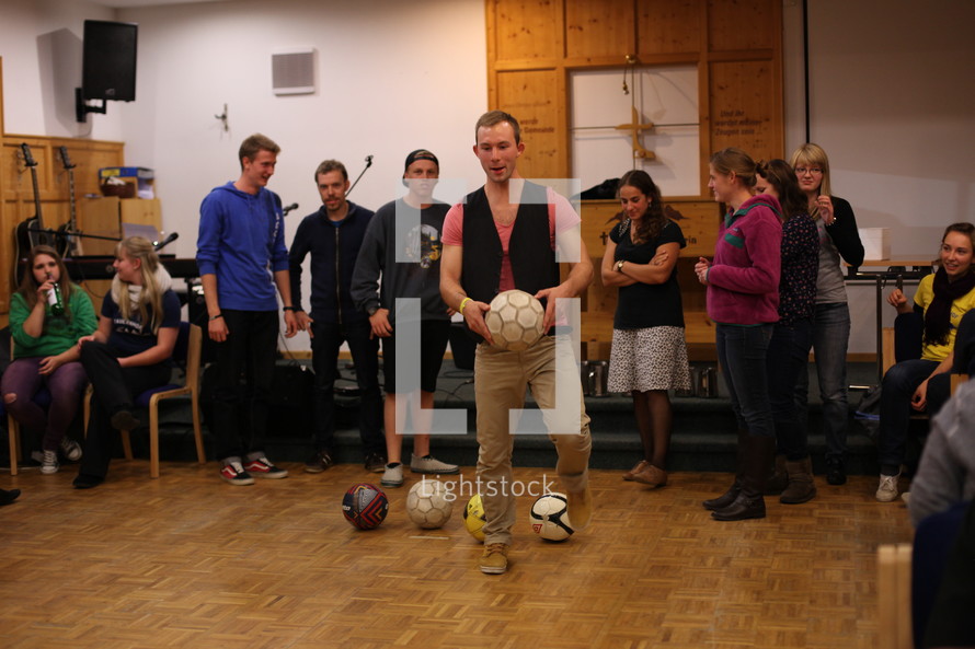 young adults in a choir room with soccer balls 