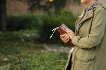a young woman holding a Bible outdoors 