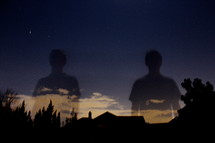 Two towering shadows of men in the night sky.