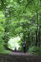father and son walking on a path in the woods 