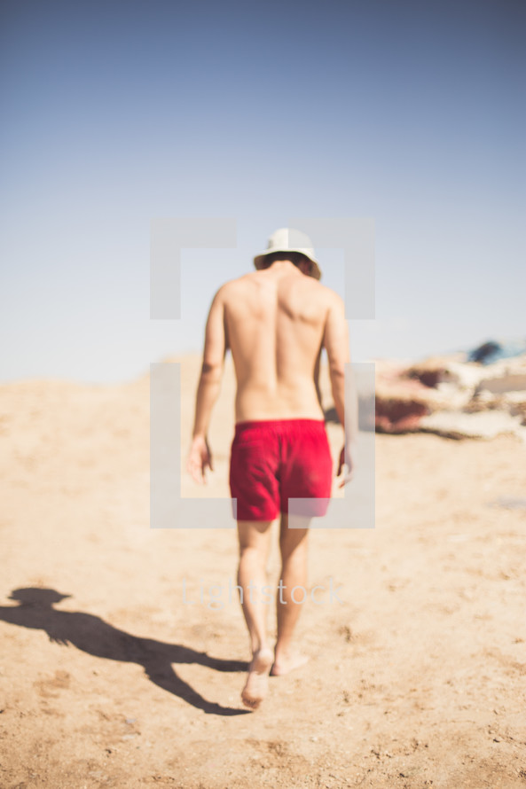 man in a swim suit walking on a beach 