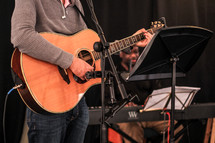 a man standing on stage playing an acoustic guitar 