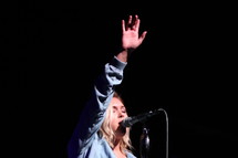 a woman singing into a microphone with a raised hands 