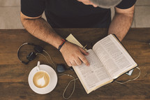 a man writing in a notepad and reading a Bible