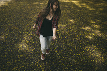 teen girl walking through a field of yellow wildflowers 