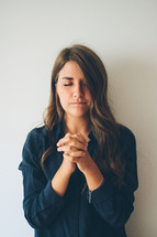 woman with closed eyes and praying hands 