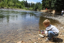 a toddler boy fishing in a pond 