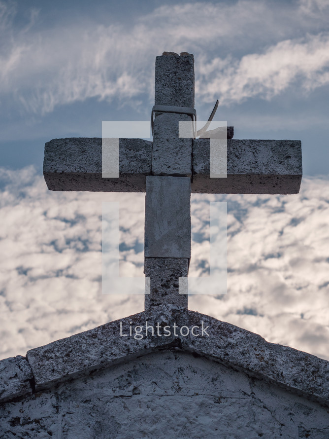 a stone cross against a cloudy sky