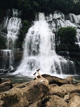 man's legs and a cascading waterfall 