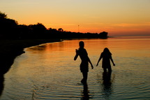 Silhouette of girls in the ocean at sunset.