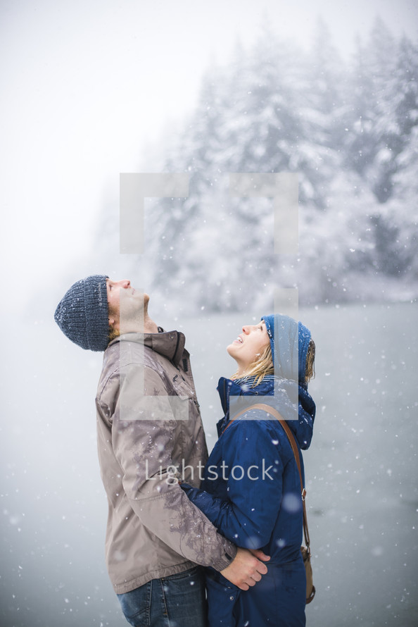 a couple holding each other in winter snow 