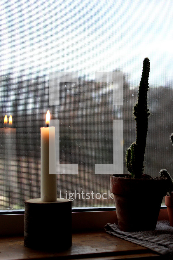 candle and cactus in a window 