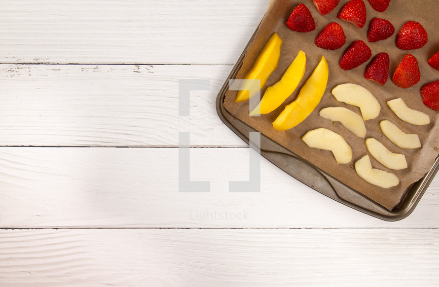 A Tray of Fruit Being Prepared to Dehydrate on a Wooden Table