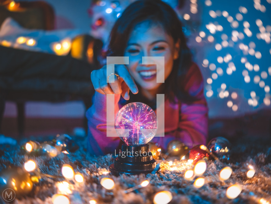 a woman touch a static electric orb and fairy lights 