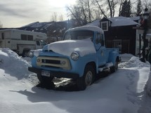 A vintage blue truck in the snow.