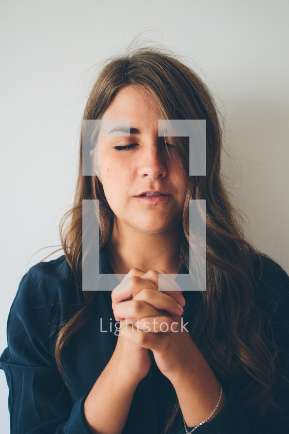 woman with closed eyes and praying hands 