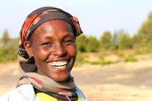 African woman with a huge smile wearing a traditional head scarf 