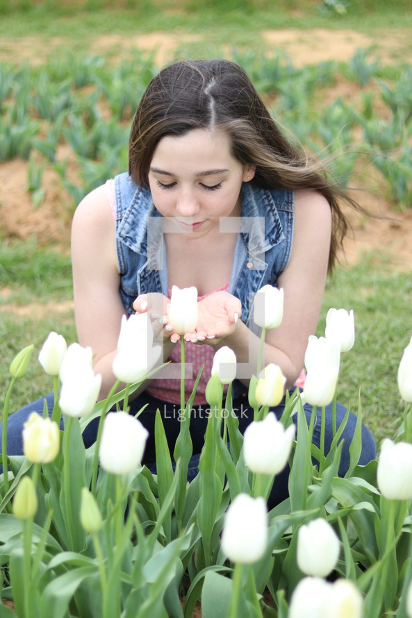 a girl smelling white tulips 