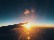 the wing of a plane in flight at sunset 