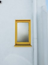 yellow mirror hanging on a white wall 