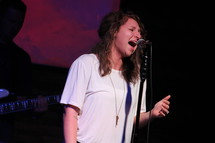 woman singing into a microphone on stage 