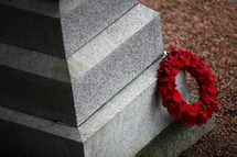 A red funeral wreath on a cemetery headstone.