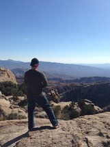 a man standing on a desert mountain taking in the view 