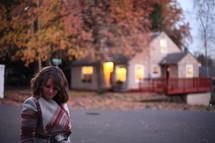 a woman in a coat in fall standing outdoors looking down 