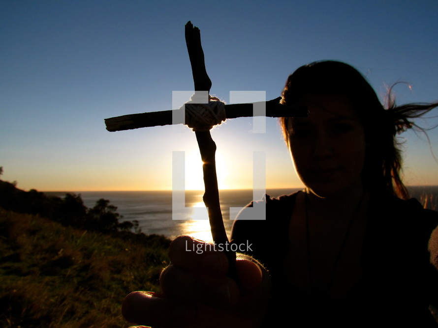 teen girl holding a cross made out of sticks 