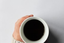hand in a sweater on a coffee mug 