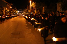 procession of people walking through the streets carrying candles 