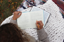 woman reading a Bible outdoors in fall under a blanket 