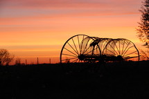 silhouette of a hay baler at sunrise