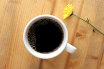 coffee mug and yellow flower on a wood table 