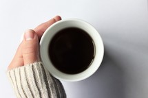 hand in a sweater on a coffee cup 