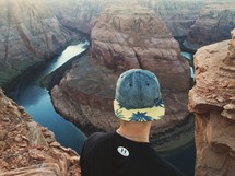 man looking down at a river in a canyon 