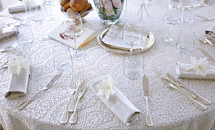 White lace tablecloth on large round table set for a wedding