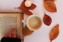 fall leaves around a latte and an open Book