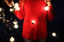 a woman holding a strand of lights 