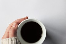 hand in a sweater on a coffee mug 