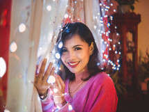 a woman holding a string of fairy lights 