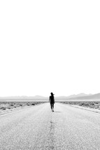 a woman walking down a desert road 