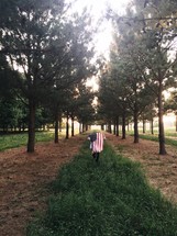 man walking with an American flag draped over his back 