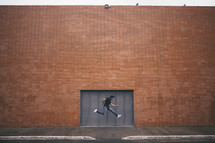 man leaping in front of a brick building 